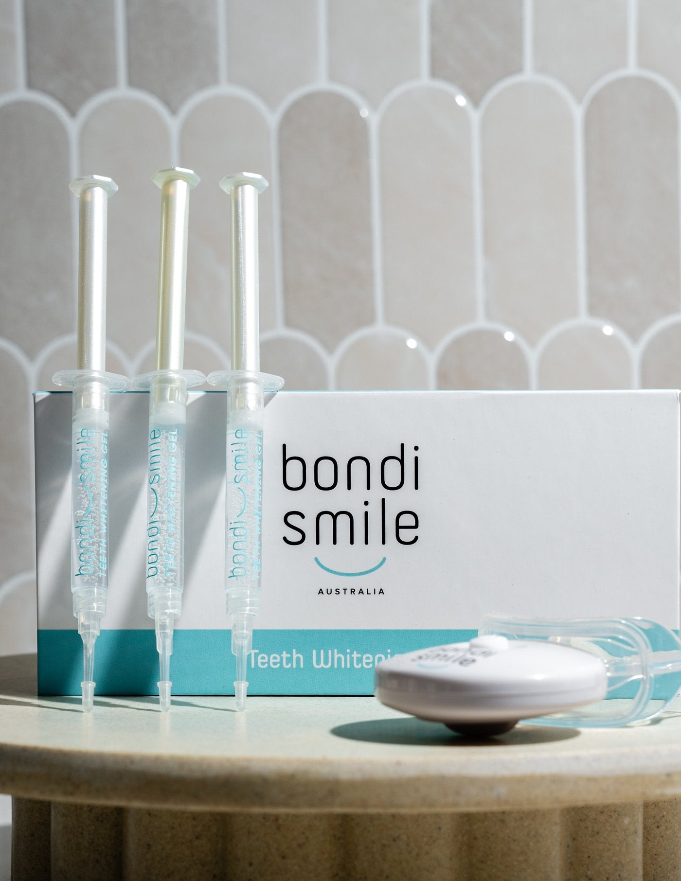 Bondi Smile Teeth Whitening Kit box, syringes and LED device against scalloped tile backdrop